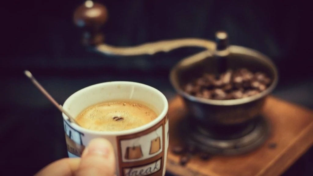 Kop koffie met koffiemolen op achtergrond