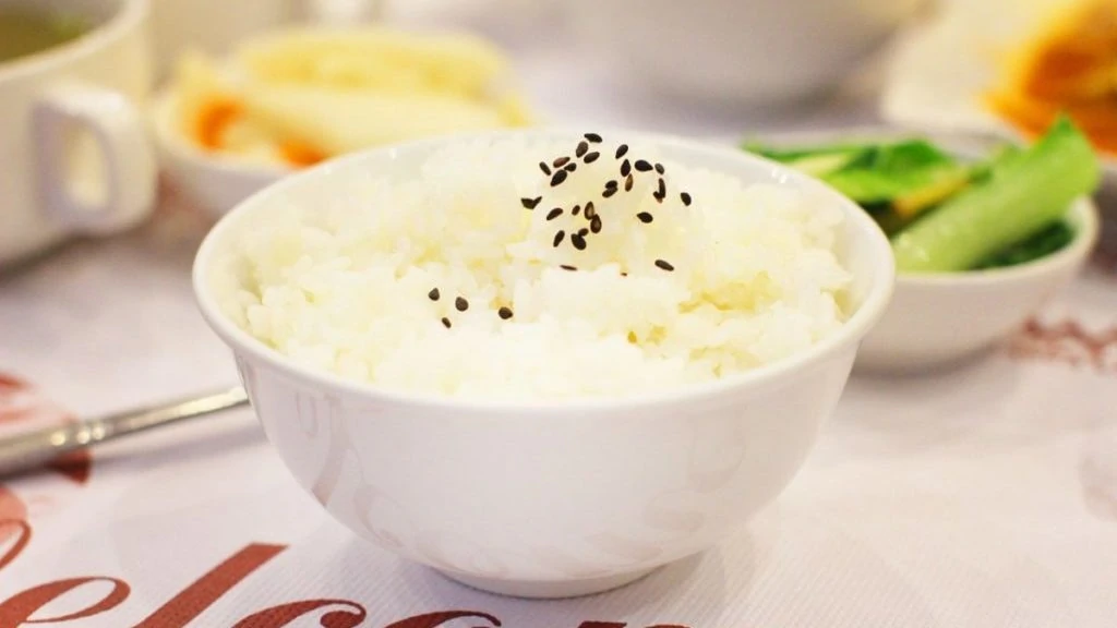 Gekookte rijst in een kommetje met zwart sesamzaad