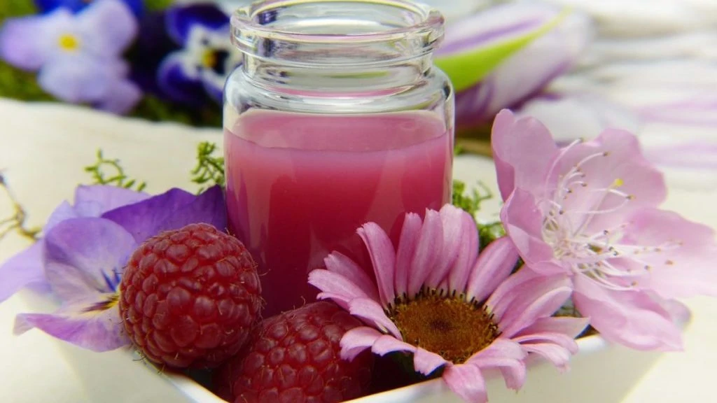 Roze smoothie in bakje met frambozen en bloemen

