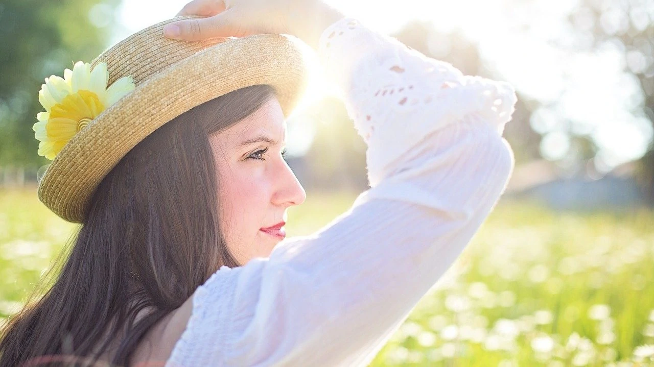 Vrouw met hoed in de zon, zij-aanzicht