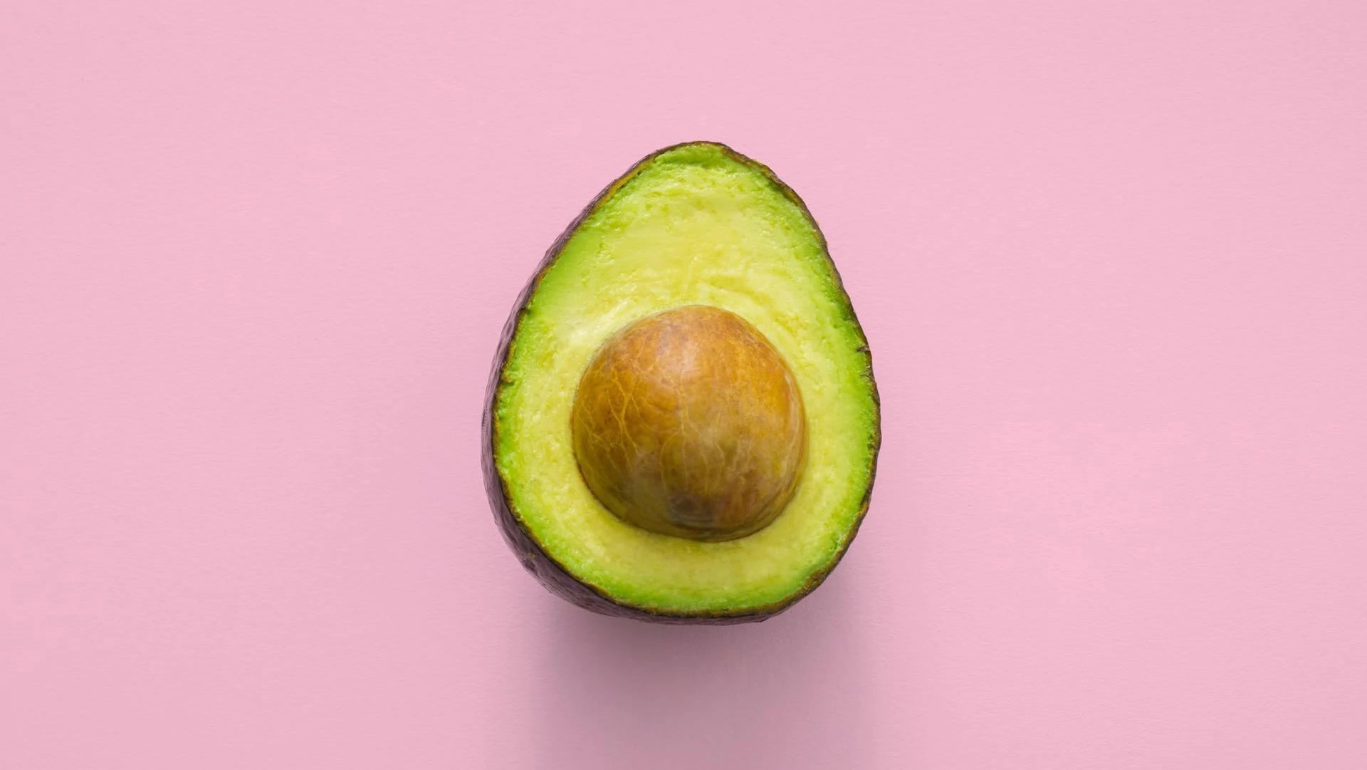 Halve avocado op roze achtergrond, bovenaanzicht