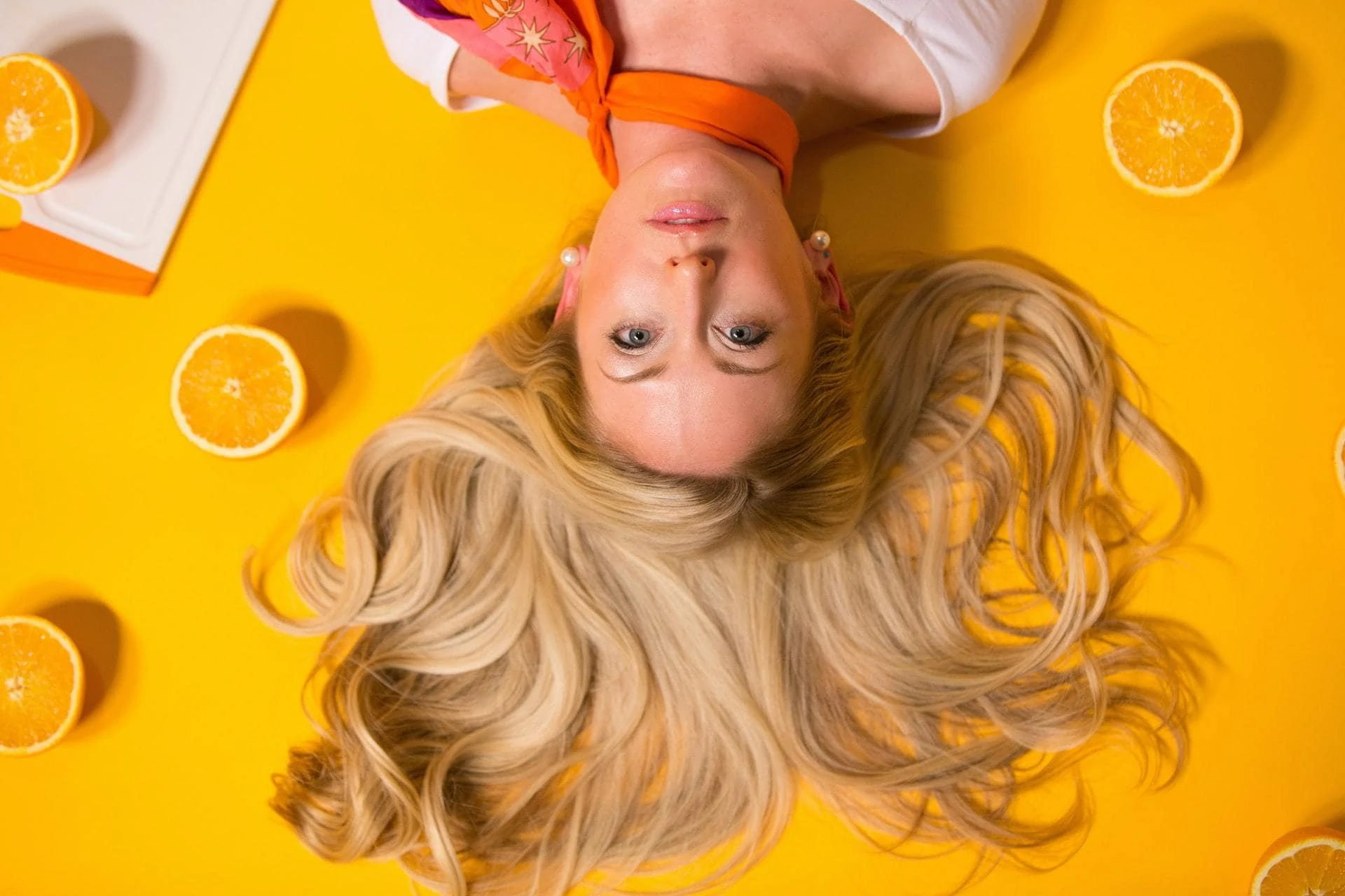 Vrouw met lang haar op gele achtergond met sinaasappels