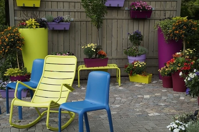 Tuin met tegels en blauwe en groene stoelen, vooraanzicht