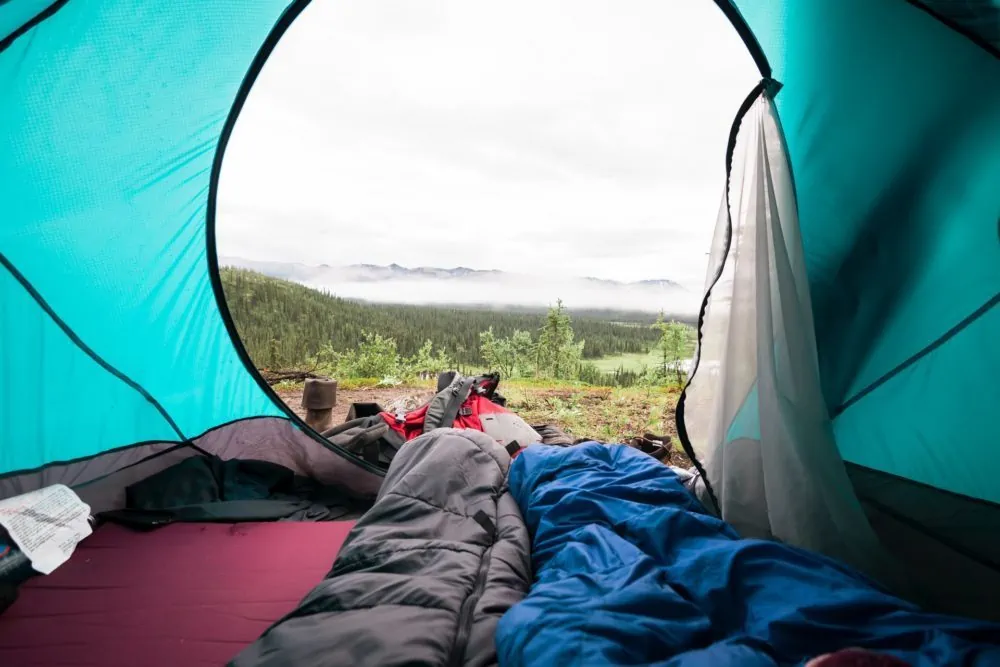 Twee slaapzakken in tent met uitzicht op de bergen