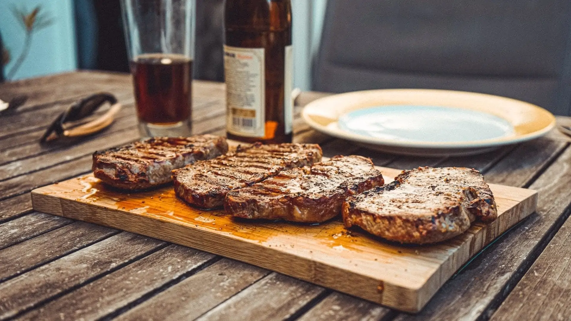 Vier steaks op houten snijplank, vooraanzicht
