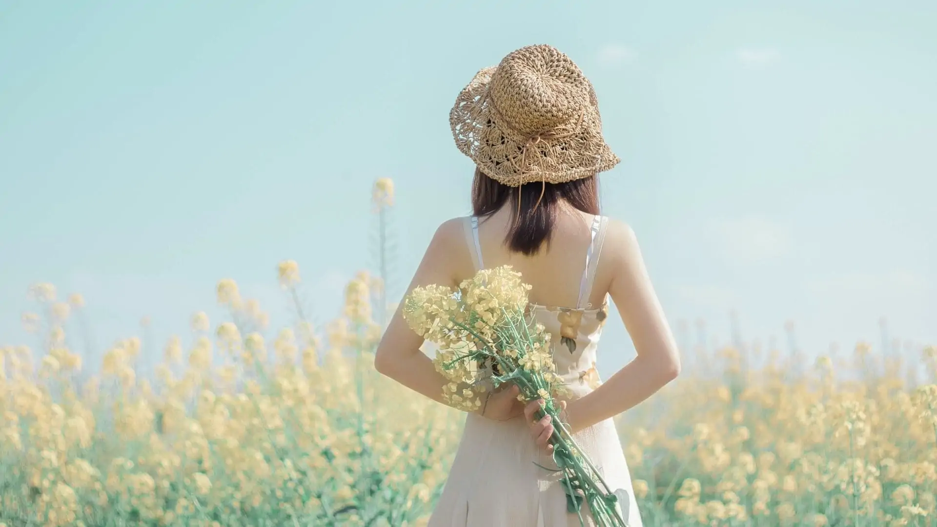 Vrouw in veld met bloemen achter haar rug