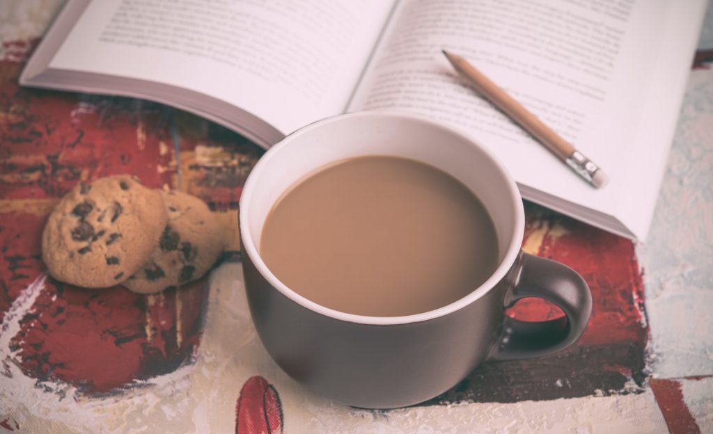 Kop koffie met boek en koekjes, bovenaanzicht, schuin.