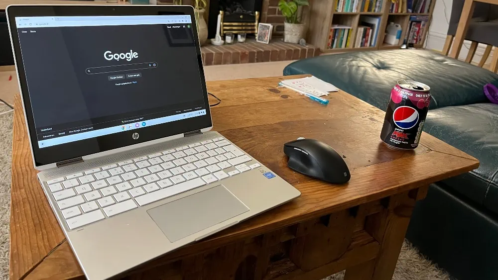 Chromebook op tafeltje met muis en blikje pepsi ernaast
