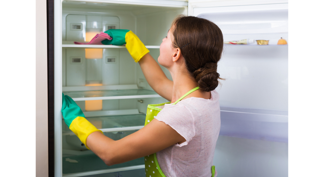 Vrouw met geel groene rubberen handschoenen maakt koelkast schoon